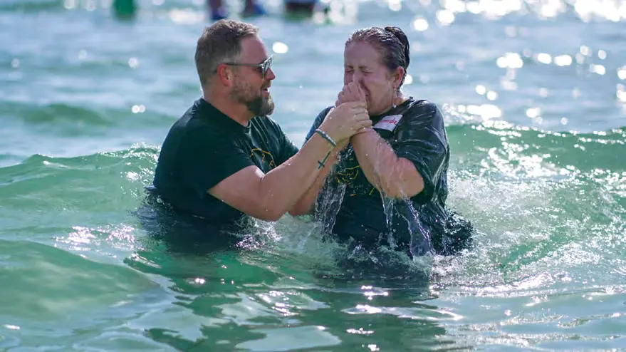 Two people laughing and celebrating during a baptism in the ocean
